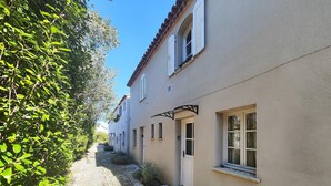 Eine enge Kopfsteinpflasterstraße gesäumt von traditionellen Gebäuden, mit einem Steinweg und üppiger Bepflanzung an einer Seite.