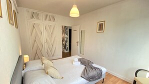 Une chambre à coucher comprenant un lit, une table de chevet, une chaise, une armoire et une porte.