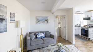 A modern living room with a grey sofa, a glass coffee table, and artwork on the walls.