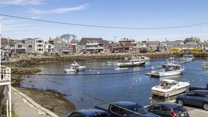 A marina with boats docked, a river, and residential buildings in the background.