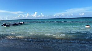 A boat anchored near the shore with clear turquoise water and a calm sea. - Newly Renovated!! COCO PALMS - Exclusive villa with private pool/beach access.  (Mammee Bay, Mammee Bay Estates)