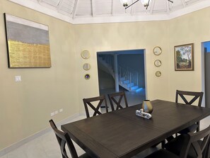Une salle à manger avec une grande table, des chaises et une pancarte « Bienvenue ». On y trouve également des miroirs fixés au mur et un tableau.