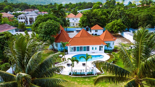 A large house with a swimming pool surrounded by palm trees. - Newly Renovated!! COCO PALMS - Exclusive villa with private pool/beach access.  (Mammee Bay, Mammee Bay Estates)