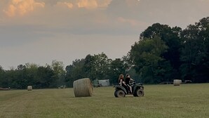 A wide-open field with hay bales and a tractor with two people riding. - Primitive Country Camp Spot for Total Eclipse April 8, 2024! 2:38 Mins Totality (Benton)