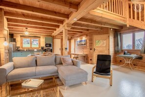 A cozy log cabin interior with a living room, dining area, and kitchen.