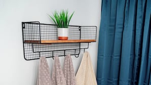 A bathroom with a shower curtain, towels, a toilet paper holder, and a plant on a shelf. - JC Entire Apartment remodeled, close to Airport and Ferry (Coram)