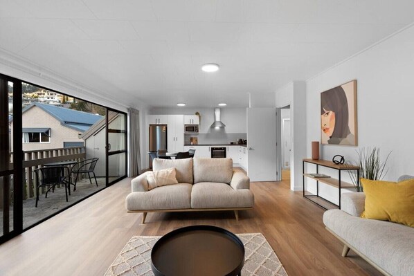 A modern living room with a sofa, a coffee table, and a dining area with chairs. - 5 minute walk to Queenstown, car park and mountain views. (Queenstown)