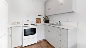Eine moderne Küche mit weißen Schränken, einem Backofen, einer Spüle und einer Holz-Fischgräten-Spritzschutzleiste.