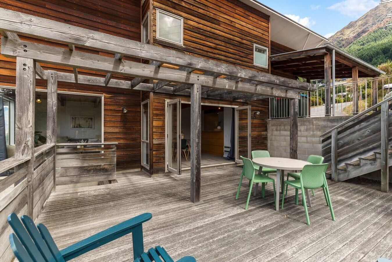 Une terrasse en bois avec une table et des chaises, un escalier et un bâtiment dont le revêtement extérieur est en bois.