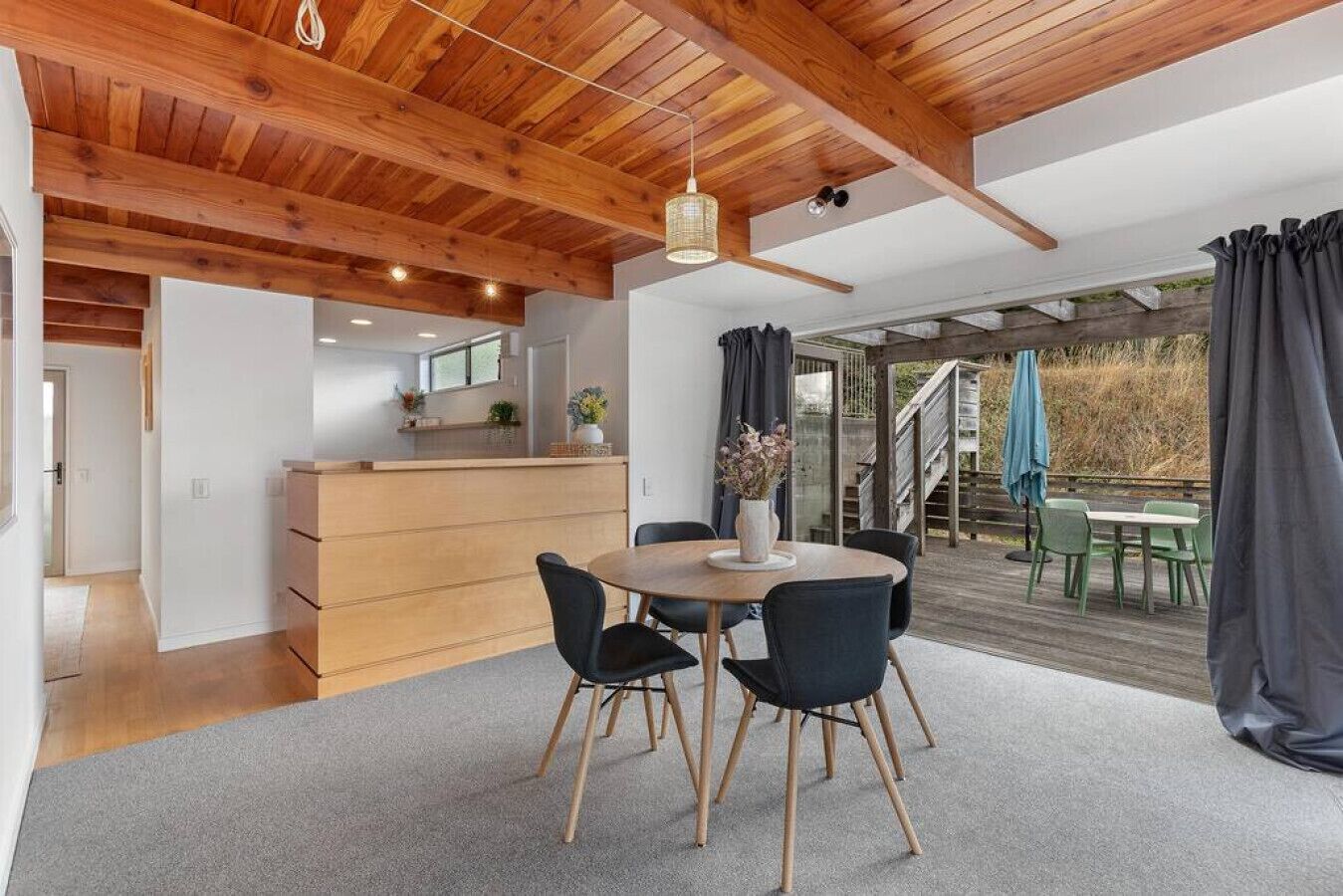 A modern kitchen with wooden cabinets and a dining area with a round table and chairs.