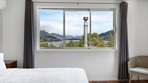 A bedroom with a large window offering a view of mountains and a lake. - Mountain and lake views, loads of parking and a wood burning fire (Queenstown)