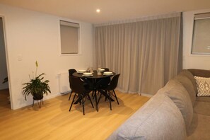 A modern living room with a dining area, a sofa, and a potted plant. - 5 minute easy walk to Queenstown, warm and spacious. (Queenstown)
