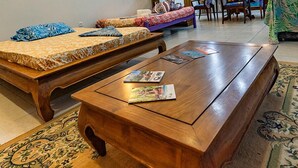 Un soggiorno accogliente con un tavolino in legno, un divano e una libreria. Presente una ventola a soffitto e un'area pranzo con tavolo e sedie.