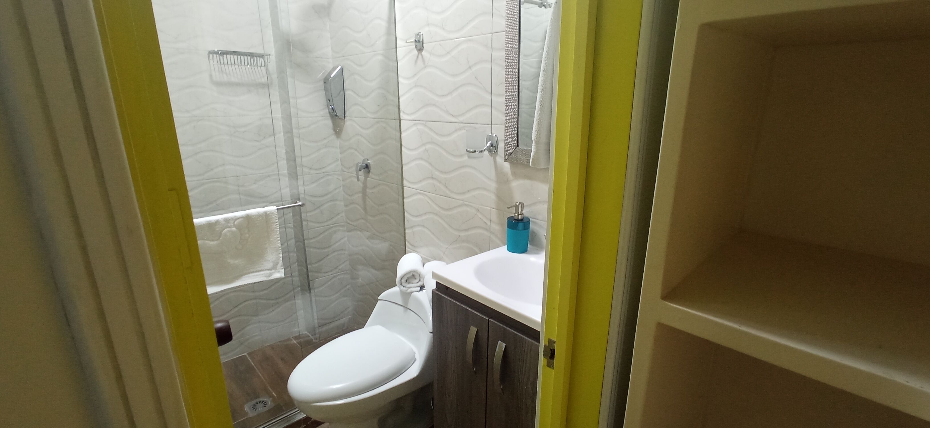 A bathroom with a toilet, shower, and sink.