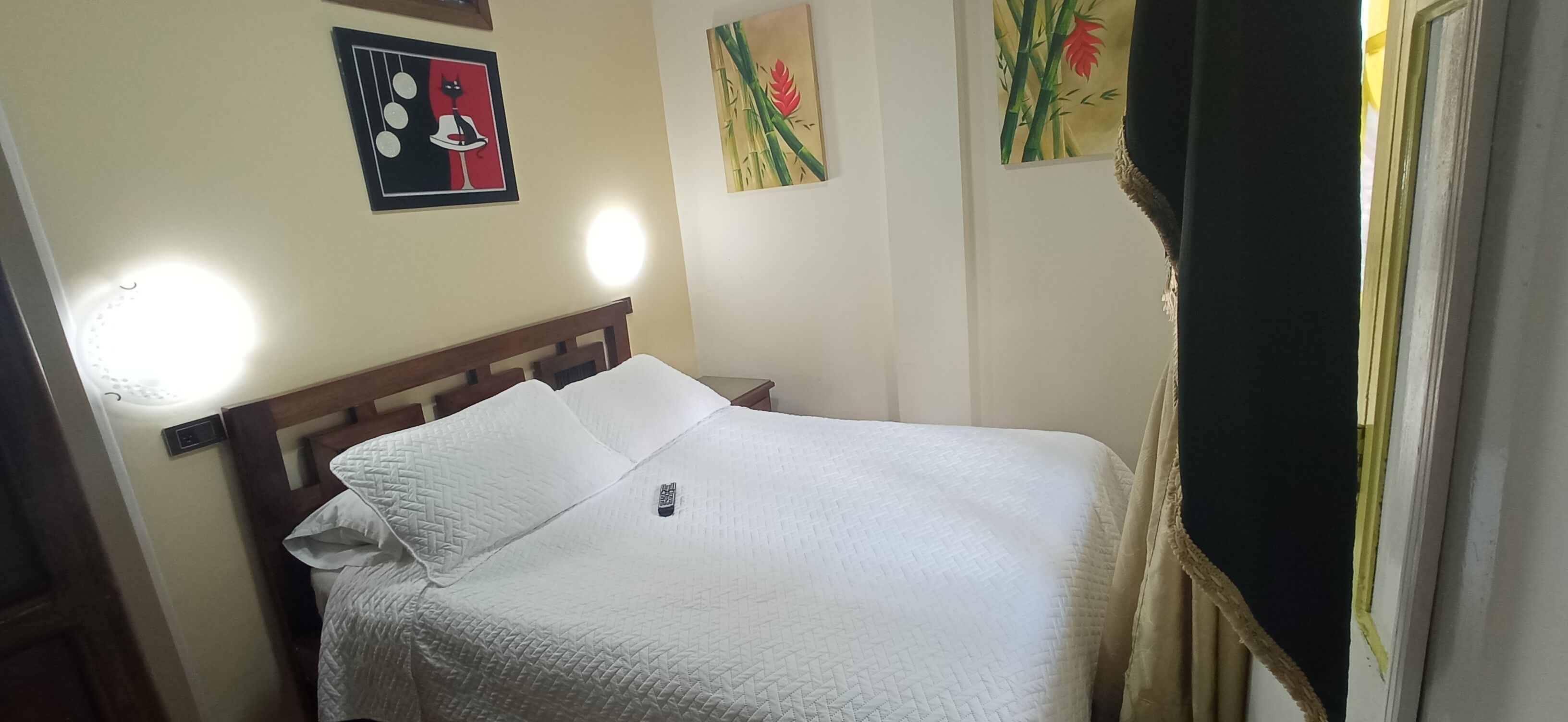 A neatly made bed with a white quilt, a wooden headboard, and a bedside table with a lamp.
