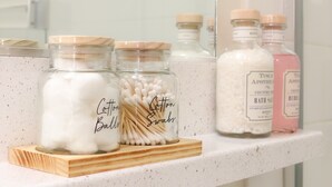 A bathroom shelf with jars of cotton balls, cotton swabs, and bath salts. - Santa Monica Ocean View Suite (Santa Monica)