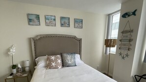 A bedroom with a large bed, a nightstand, a lamp, and wall decorations including framed pictures and a sign. - Santa Monica Ocean View Suite (Santa Monica)