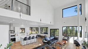 A spacious, modern interior with a kitchen, dining area, and living space, featuring large windows and a fireplace. - The Falcon- Breathtaking Mountain Views (Rapid City)