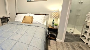 Une chambre à coucher avec un lit, une table de chevet, une lampe et un tableau au mur.