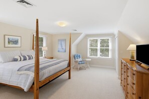 A bedroom with a four-poster bed, a chair, a dresser, and a television.