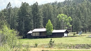 Une cabane dotée d’une grande terrasse, entourée d’une forêt et d’un lac.