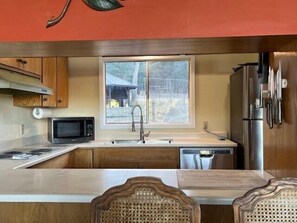 A compact kitchen with wooden cabinets, a microwave, a sink, and a refrigerator.