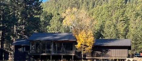 Un edificio de estilo rancho con un porche amplio y un terreno cercado con animales pastando.