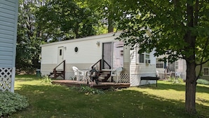 A mobile home with a porch, outdoor seating, and a small garden area. - Park model unit #2 for rent by Silver Lake NY  (Perry)
