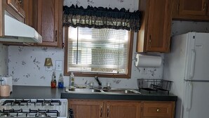 A kitchen with wooden cabinets, a gas stove, a sink, and a refrigerator. - Park model unit #2 for rent by Silver Lake NY  (Perry)