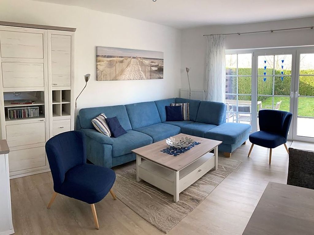 A modern living room with a blue sofa, a coffee table, and a bookshelf.