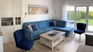 Moderni olohuone, jossa on sininen sohva, sohvapöytä ja kirjahylly.