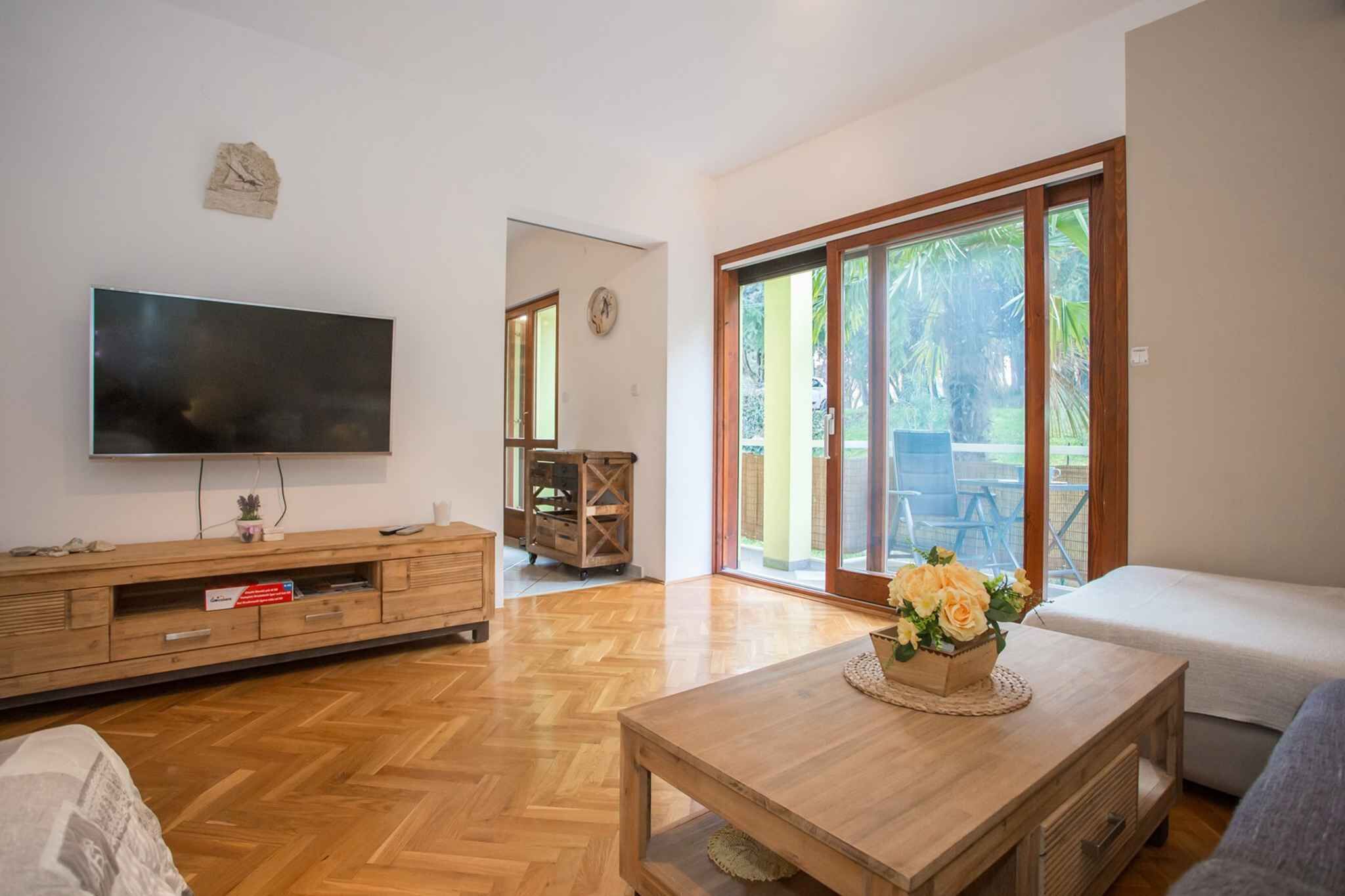 A living room with a flat-screen TV, wooden furniture, a sofa, and a sliding glass door leading to an outdoor area.