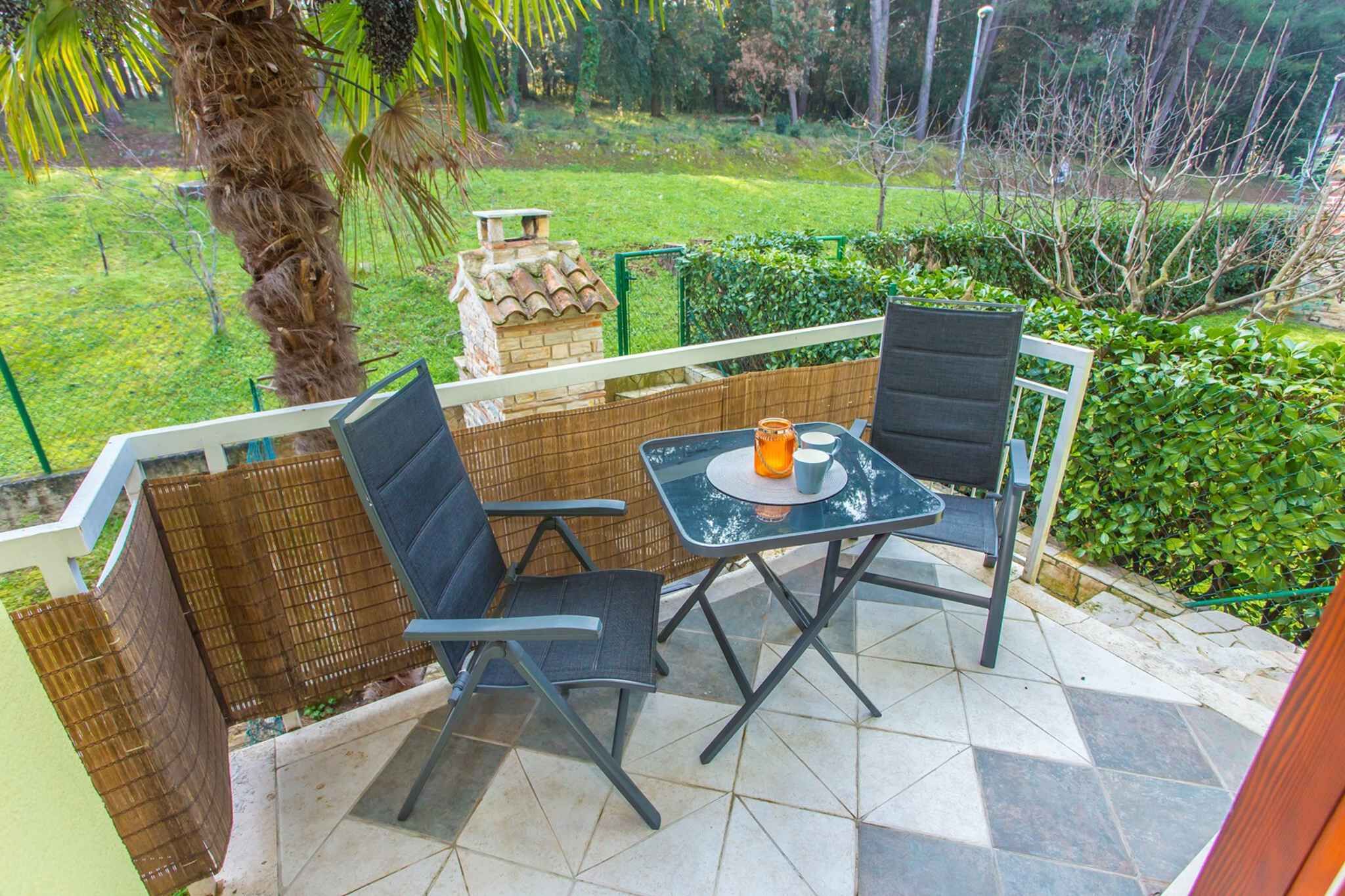 A patio with a table and chairs, a small brick structure, and a view of a green garden.