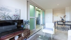 A modern living room with a flat-screen TV, a coffee table, and a white armchair. - Amazing apartment in Los Alcázares (Los Alcázares)