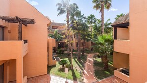 A courtyard with palm trees, a tiled walkway, and buildings with a consistent architectural style. - Amazing apartment in Los Alcázares (Los Alcázares)