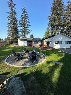 A modern house with a patio area featuring outdoor seating and a fire pit. - The Sprout  - gas fire-pit, grilling staton, hot tub, close to shops & hiking (Juneau)