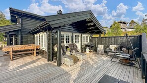 A wooden deck with outdoor furniture, a covered seating area, and a grill. - 3 bedroom lovely home in Bjorli (Bjorli)
