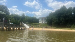 A wooden pier extending into a body of water with a white slide. - Cozy River View House (Nanjemoy)