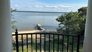 A view of a lake from a balcony with a wooden dock extending into the water. - Cozy River View House (Nanjemoy)