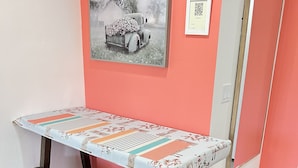 A table with a floral tablecloth and wooden stools, set against a pink wall with a framed picture above. - Private Suite with Washer and Dryer, Kitchenette  and Enclosed Parking (Las Cruces)