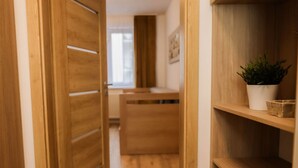 Un couloir en bois avec une plante posée sur une étagère, des portes en bois et un bureau à l’arrière-plan.