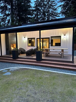 Une maison moderne dotée d’un patio couvert, de grandes fenêtres et d’une cheminée.