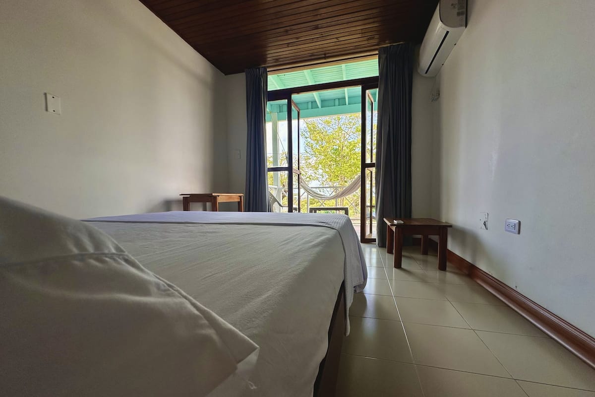 Une chambre d’hôtel avec un grand lit, une petite table et une vue sur l’extérieur par une fenêtre.