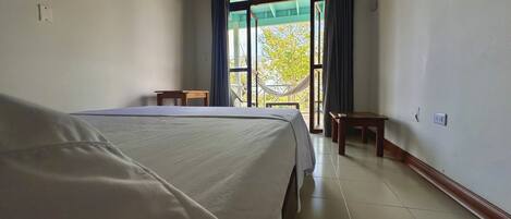 Habitación de hotel con una cama grande, una mesita y vistas al exterior por una ventana.