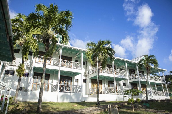 A two-story building with balconies, surrounded by palm trees.