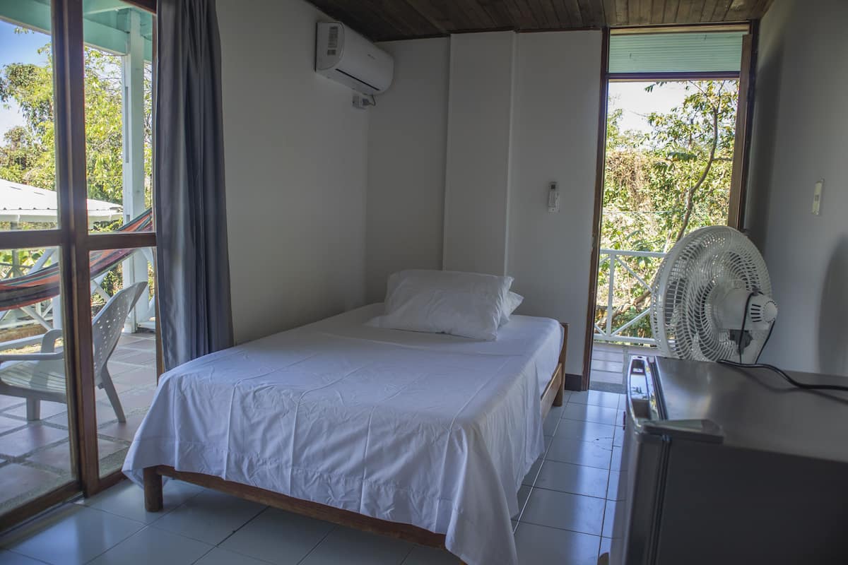 Une chambre avec un lit, un ventilateur et une vue sur l’extérieur.