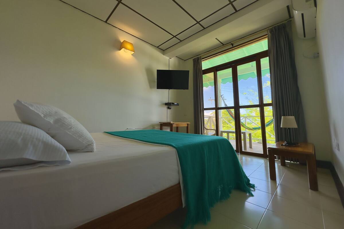 Une chambre d’hôtel équipée d’un lit, d’une télévision, d’une fenêtre donnant sur un paysage agréable et d’un appareil de climatisation.