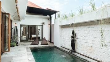 Una piscina al aire libre, sombrillas, sillones reclinables de piscina