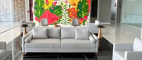 Un soggiorno moderno con un divano, due poltrone, un tavolino e un murale decorativo.