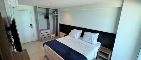 Une chambre d’hôtel avec un lit, une armoire, un bureau et un miroir.
